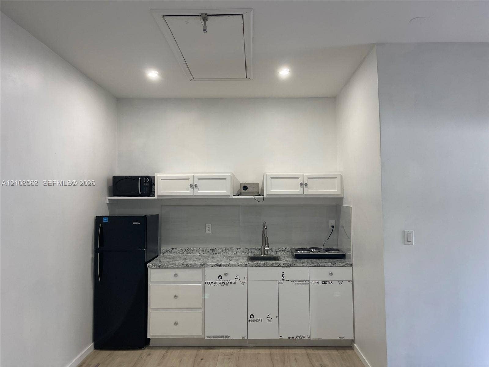 14554 SW 161 Court, #Studio, Miami, Miami, FL 33196 Kitchenette featuring white shaker-style cabinetry, stone-finish countertops, an undermount stainless steel sink with a high-arch faucet, and wood-finish flooring