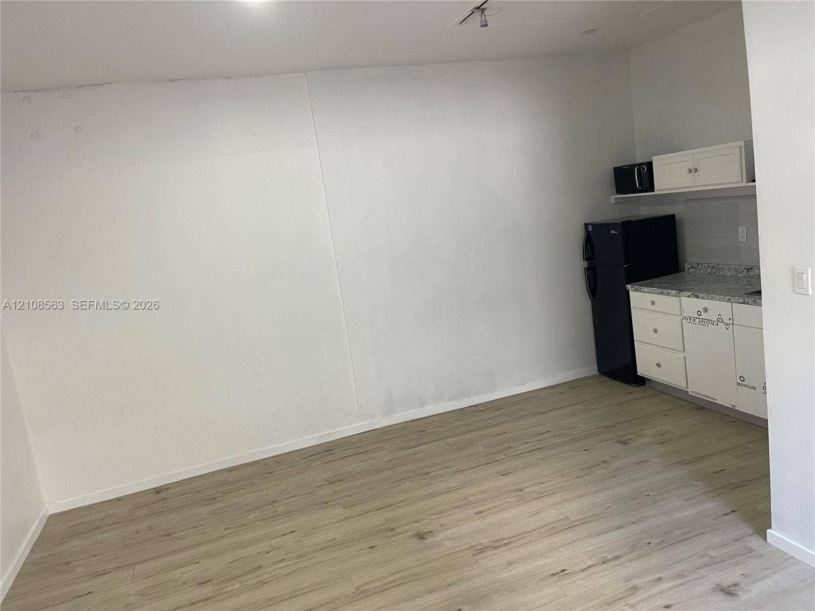 14554 SW 161 Court, #Studio, Miami, Miami, FL 33196 Kitchenette area featuring wood-finish flooring, white shaker-style cabinetry, speckled stone-finish countertops, and upper wall-mounted cabinet storage