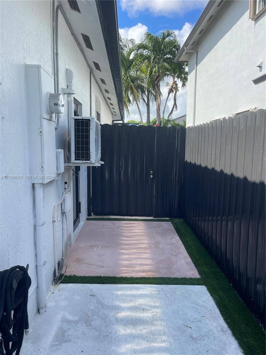 14554 SW 161 Court, #Studio, Miami, Miami, FL 33196 Side yard featuring a concrete patio, synthetic turf surfacing, and privacy fencing