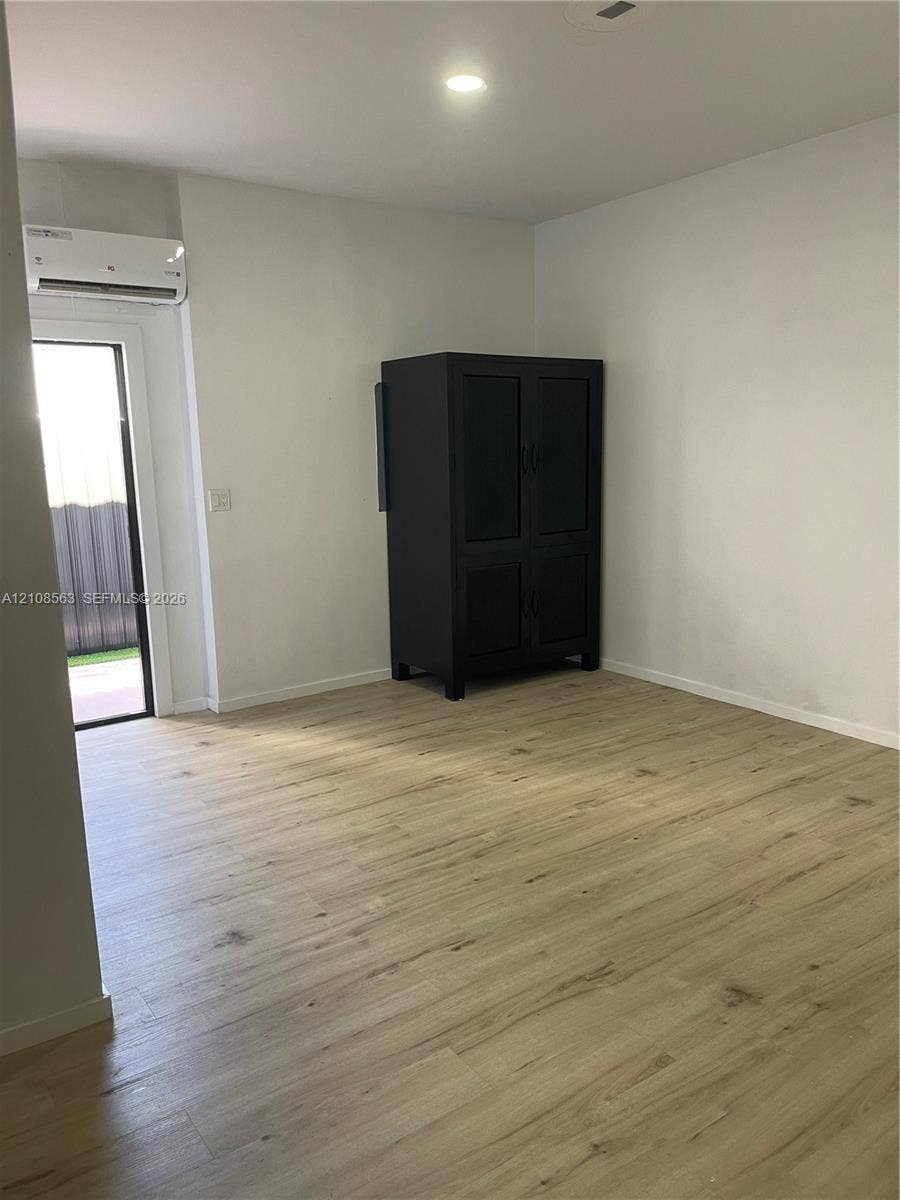 14554 SW 161 Court, #Studio, Miami, Miami, FL 33196 Room featuring wood-finish flooring, recessed lighting, and a wall-mounted ductless climate control unit with access to an exterior entry