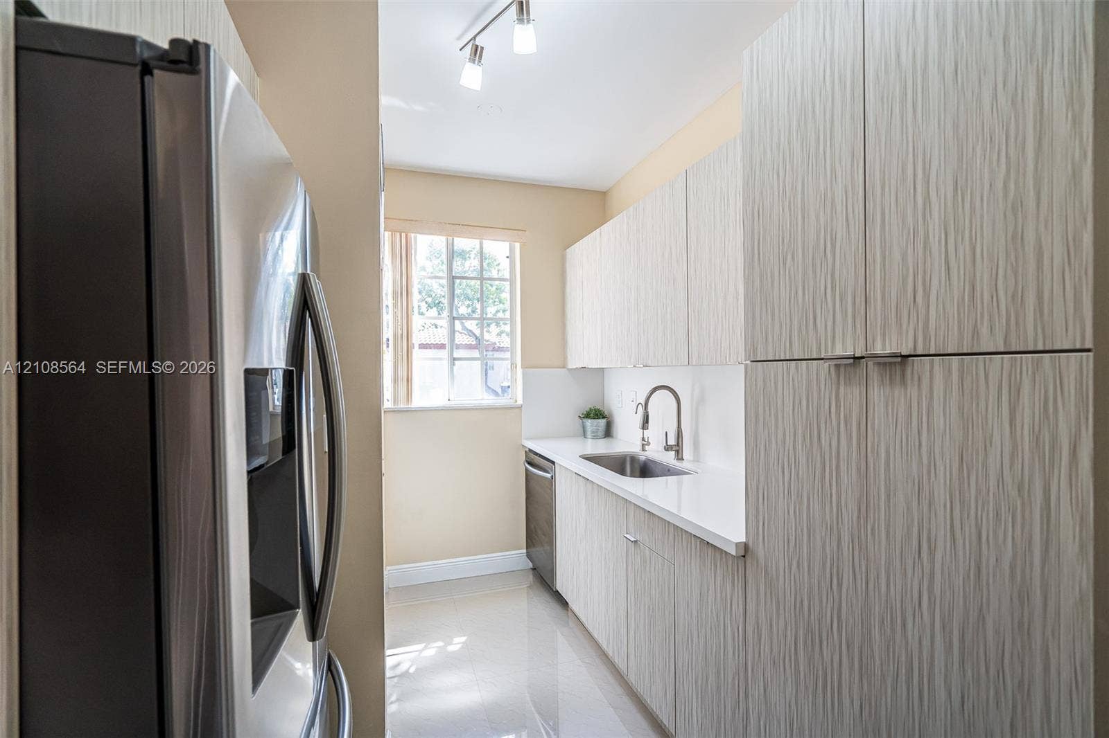 3111 NW 86th Avenue, Sunrise, FL 33351 Galley kitchen featuring textured cabinetry, white solid-surface countertops, stainless steel appliances, a high-arc faucet, and track lighting