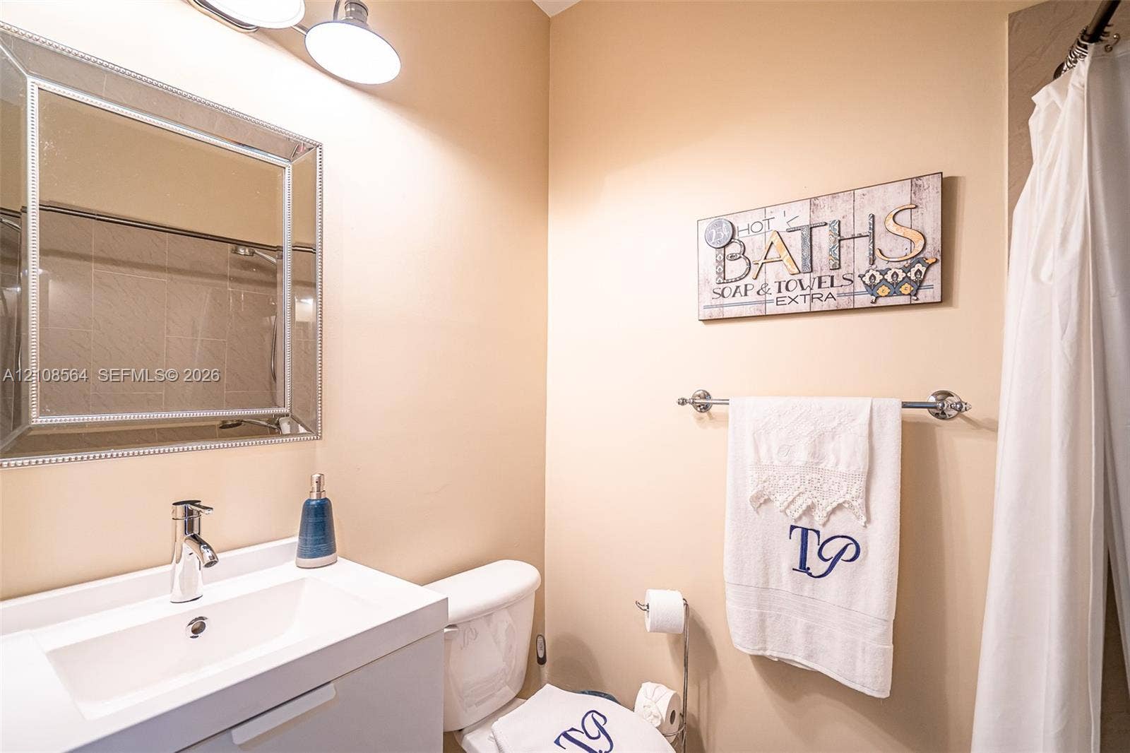 3111 NW 86th Avenue, Sunrise, FL 33351 Bathroom featuring a white vanity with integrated basin, polished chrome faucet, rectangular wall-mounted mirror, and overhead light fixture