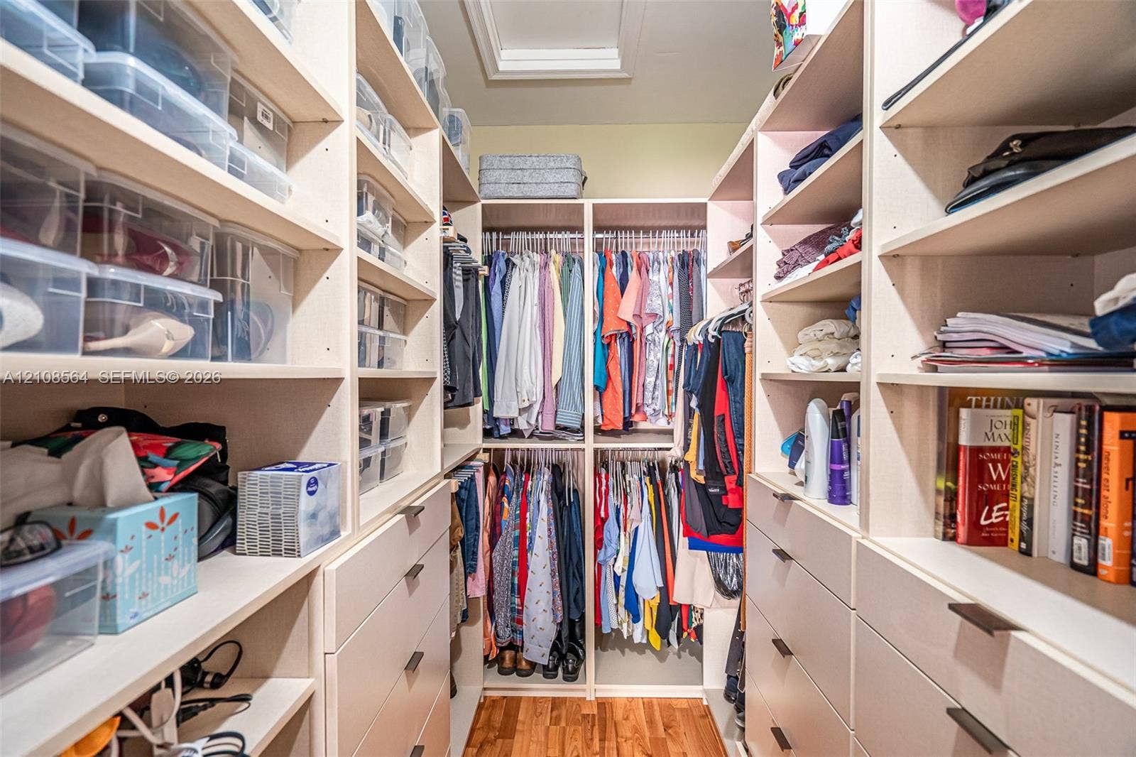 3111 NW 86th Avenue, Sunrise, FL 33351 Walk-in closet featuring extensive built-in shelving, integrated hanging rods, multiple storage drawers, and wood-finish flooring
