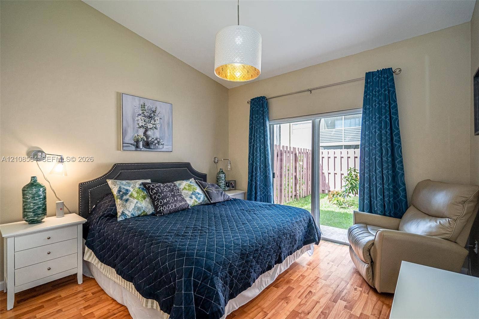 3111 NW 86th Avenue, Sunrise, FL 33351 Room featuring wood-finish flooring, sliding glass doors, a drum pendant light fixture, and two wall-mounted articulating reading lamps