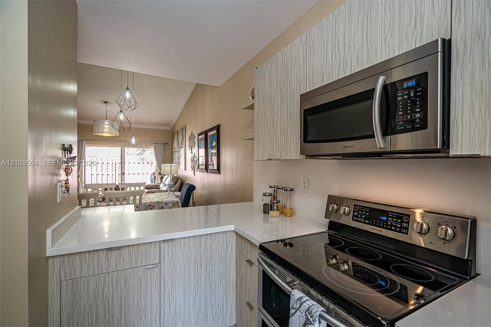 3111 NW 86th Avenue, Sunrise, FL 33351 Kitchen featuring textured cabinetry, white solid-surface countertops, built-in stainless steel microwave, and stainless steel electric range