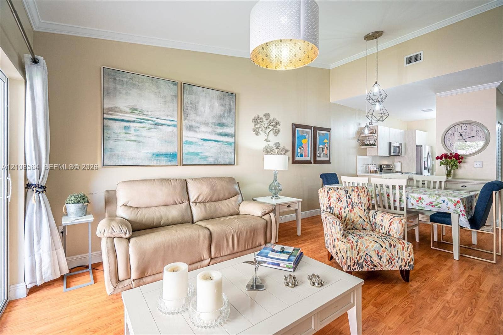 3111 NW 86th Avenue, Sunrise, FL 33351 Open-concept interior featuring wood-finish flooring, crown molding, a large drum pendant light, and geometric multi-light fixtures