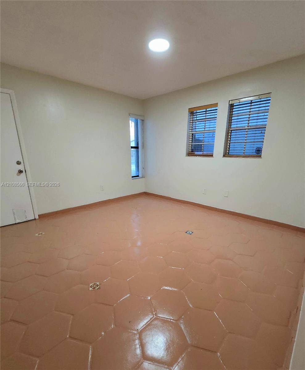 Interior room featuring hexagonal tile flooring, three multi-pane windows with horizontal blinds, and a circular recessed ceiling light