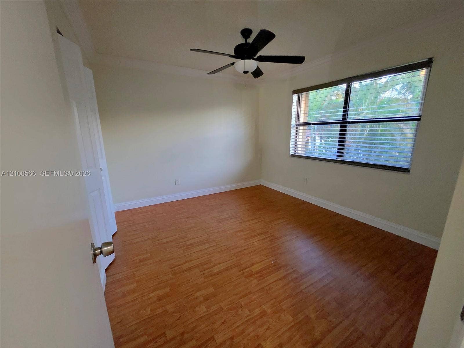 Room featuring wood-finish flooring, a multi-blade ceiling fan with integrated lighting, a dual-panel closet door, and a horizontal window with adjustable blinds