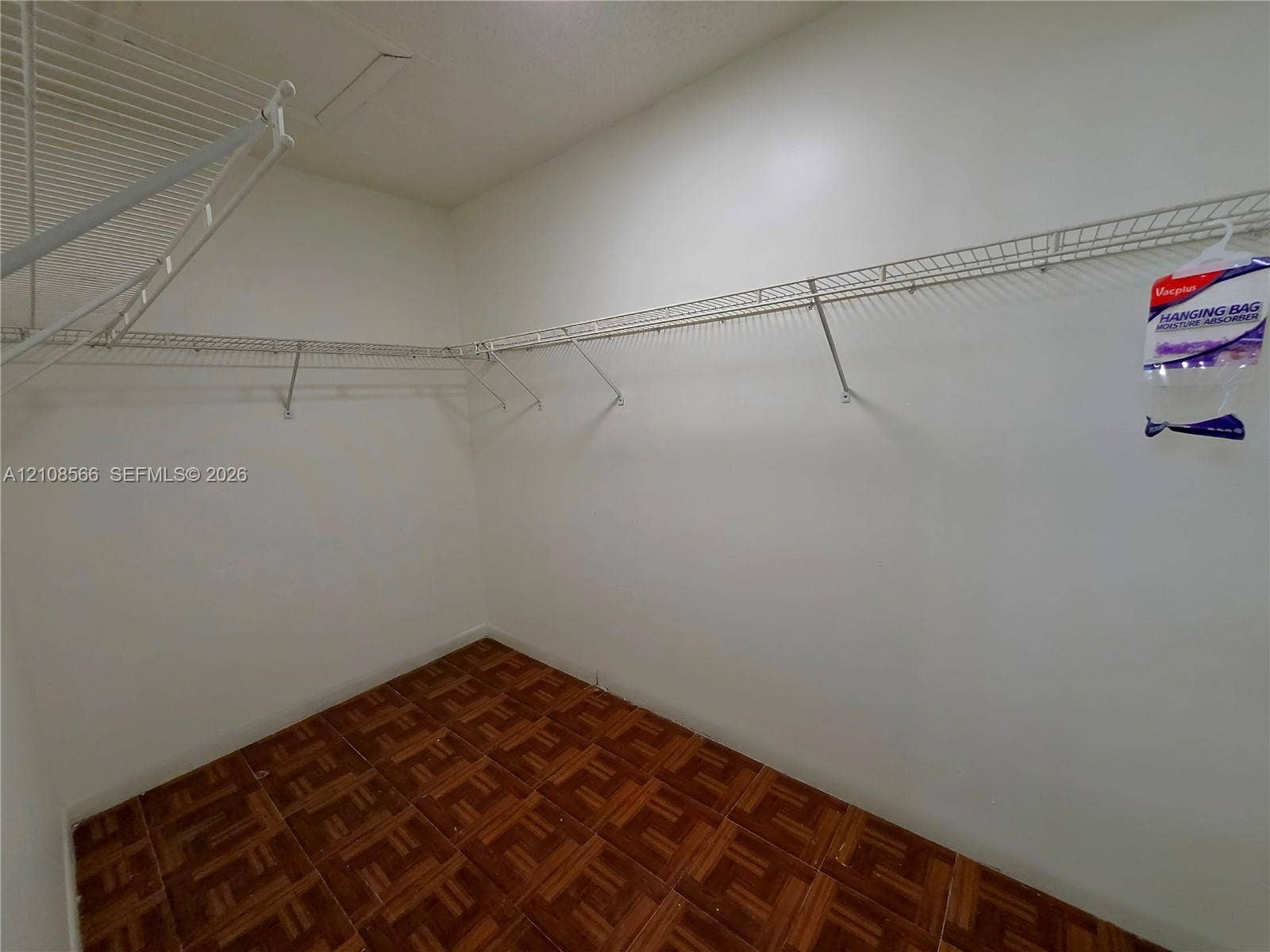 Storage space featuring white walls and wire shelving systems installed with wood-finish flooring
