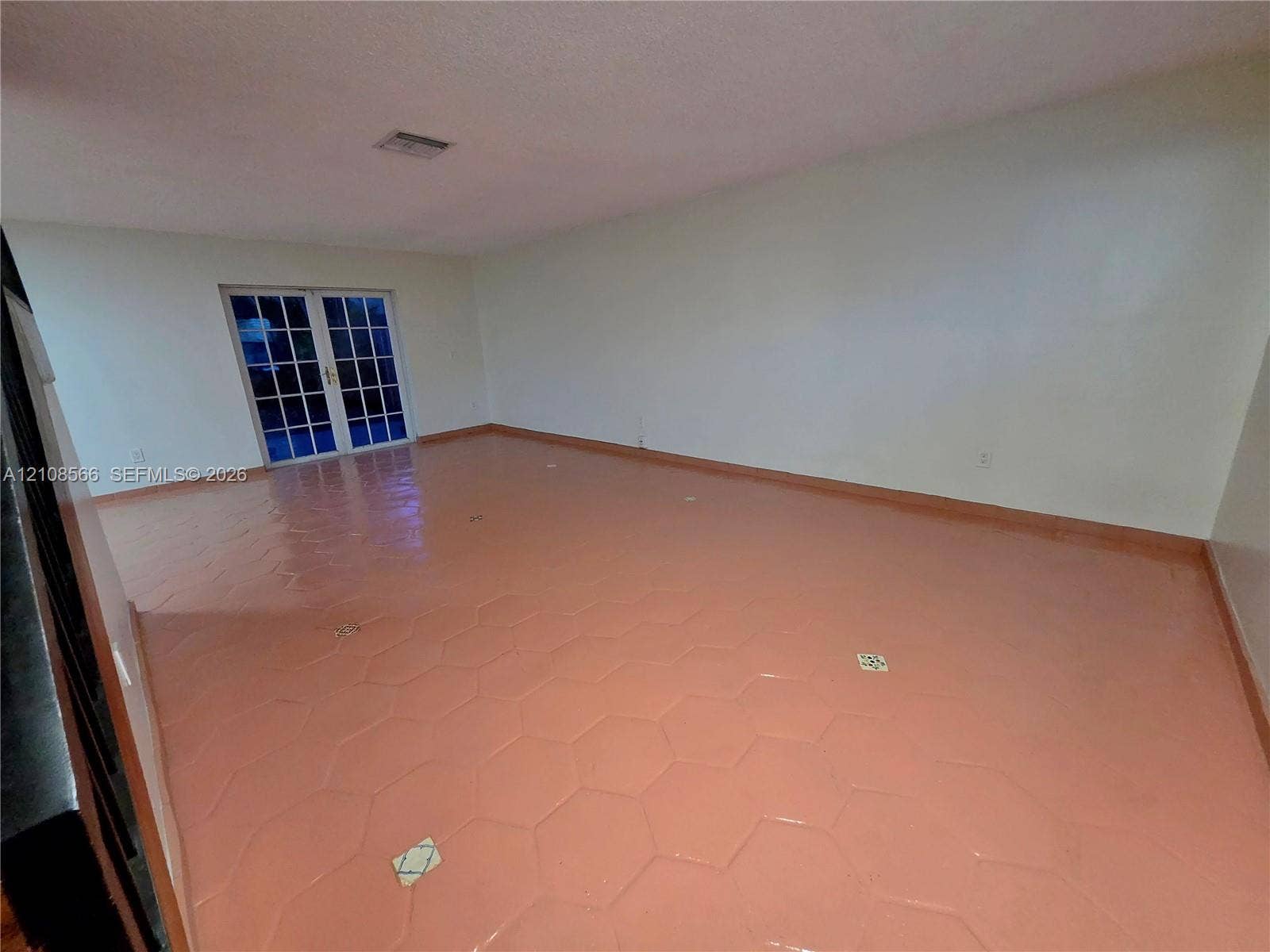 Spacious interior room featuring hexagonal tile flooring and glass-paned double doors