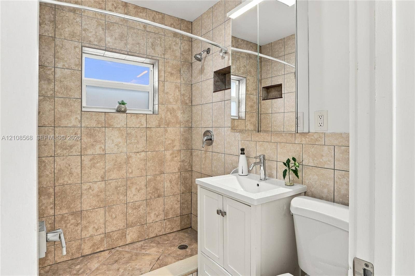 1229 NW 1st Avenue, Fort Lauderdale, Fort Lauderdale, FL 33311 Bathroom featuring tile-surround walk-in shower with inset shelving, white vanity with integrated sink, chrome-finish faucet, and mirrored medicine cabinet