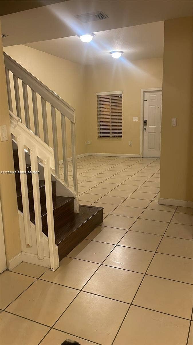 10841 SW 181st Lane, Miami, Miami, FL 33157 Entryway featuring large-format tile flooring, staircase with dark wood-finish treads and white balusters, and flush-mount ceiling lighting