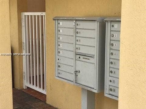 10841 SW 181st Lane, Miami, Miami, FL 33157 Wall-mounted metal mail distribution center featuring individual locking compartments and a white vertical bar gate