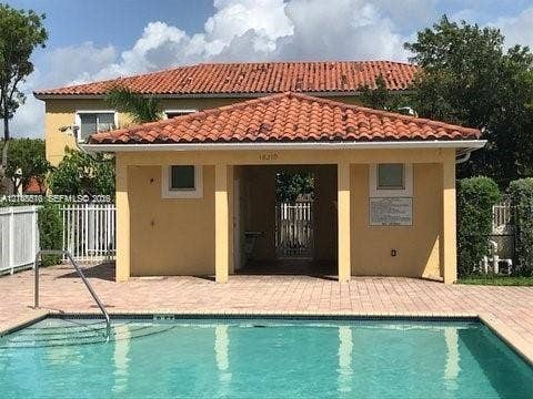 10841 SW 181st Lane, Miami, Miami, FL 33157 Swimming pool with a metal handrail and paved deck, featuring a covered pavilion with a terracotta tile roof