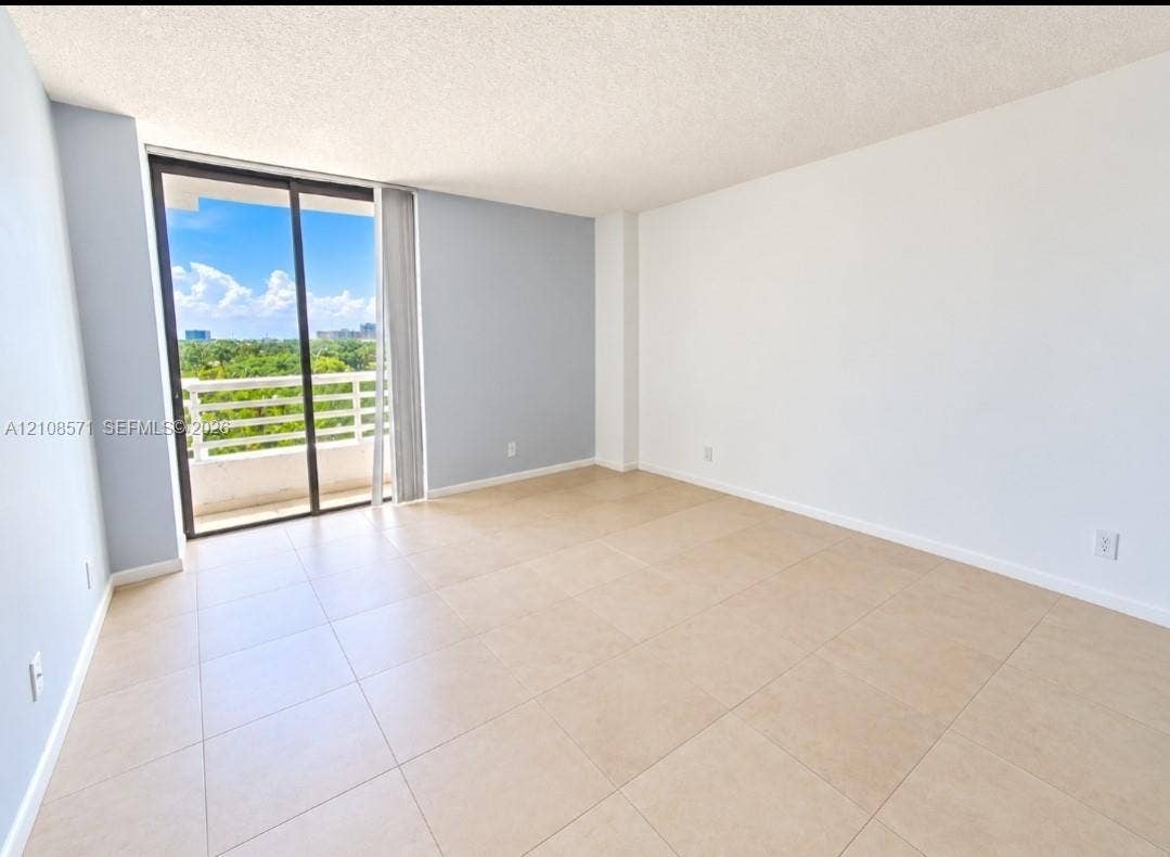 3300 NE 192nd Street, #602, Aventura, Aventura, FL 33180 Neutral-toned tile flooring, light-colored walls, and floor-to-ceiling sliding glass doors opening to a private balcony