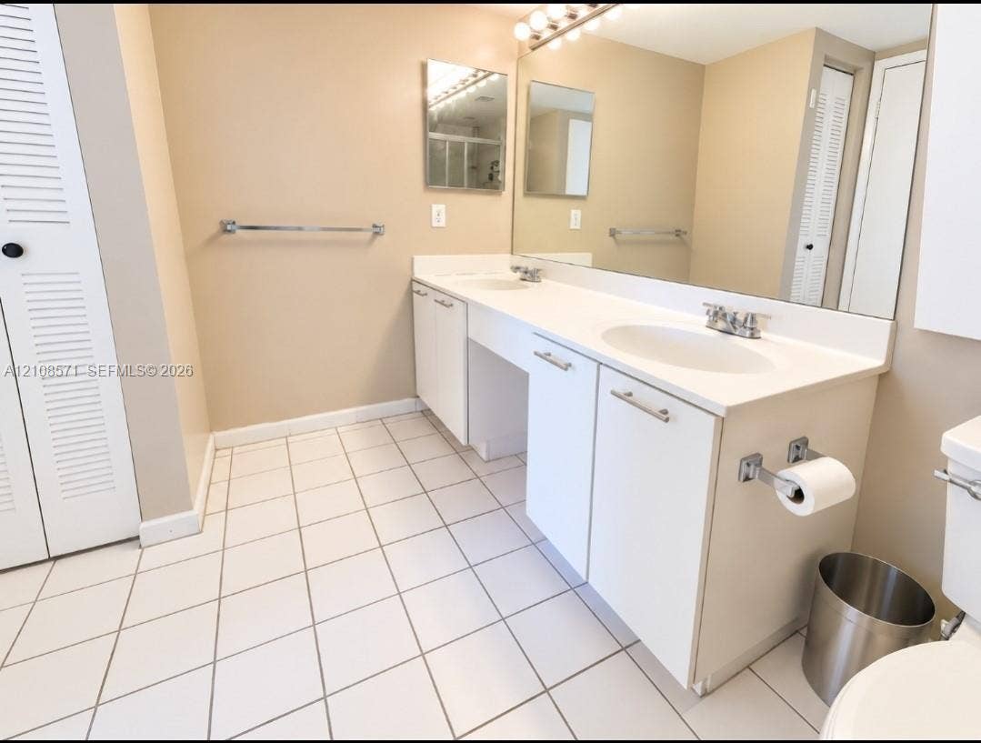 3300 NE 192nd Street, #602, Aventura, Aventura, FL 33180 Double vanity featuring white cabinetry, integrated sinks, a full-width wall mirror, and white tile flooring