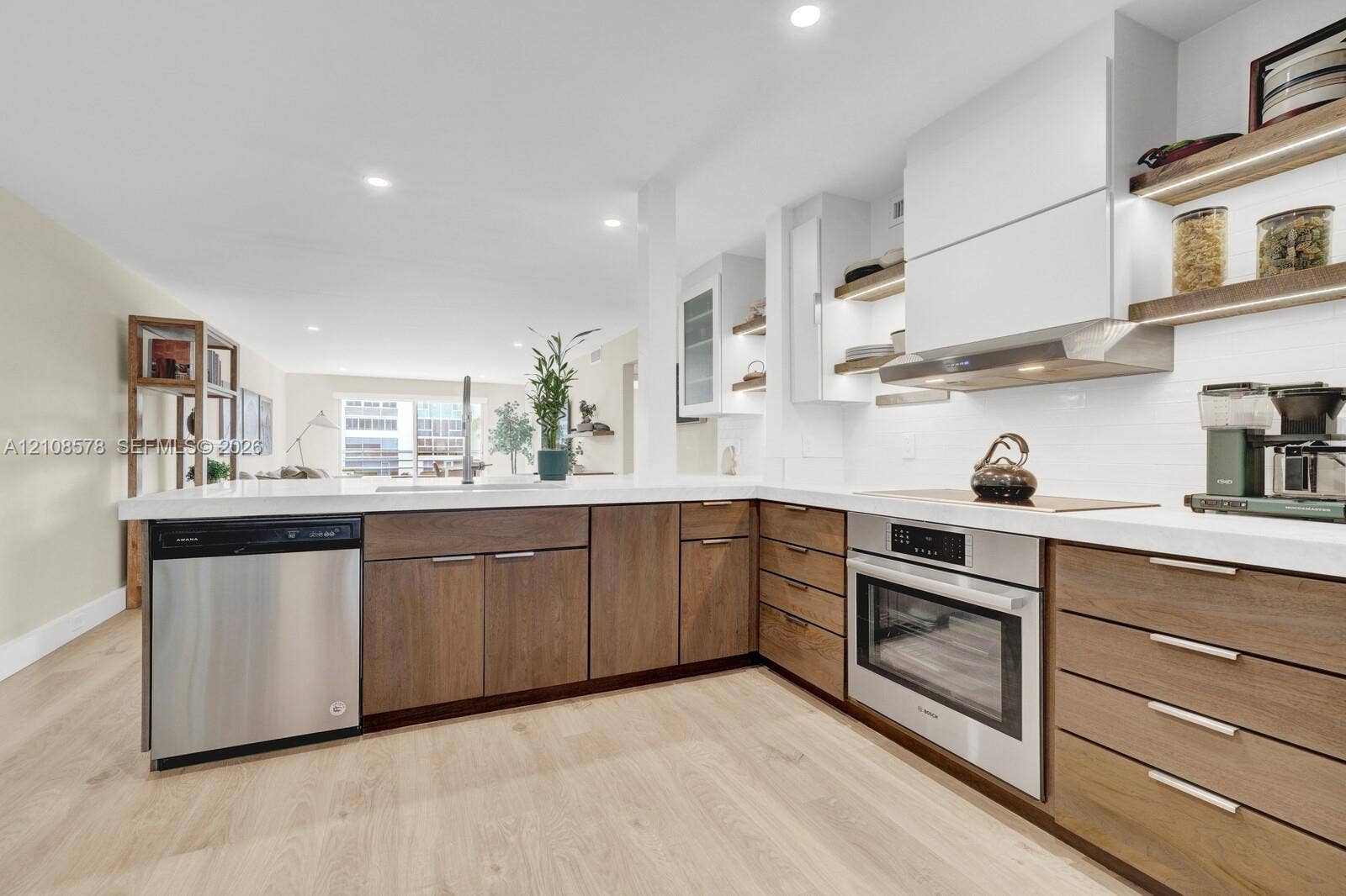 3005 Portofino Isle, #N2, Coconut Creek, Coconut Creek, FL 33066 Kitchen featuring flat-panel wood-finish cabinetry, white countertops, stainless steel appliances, open shelving with integrated lighting, and wood-finish flooring