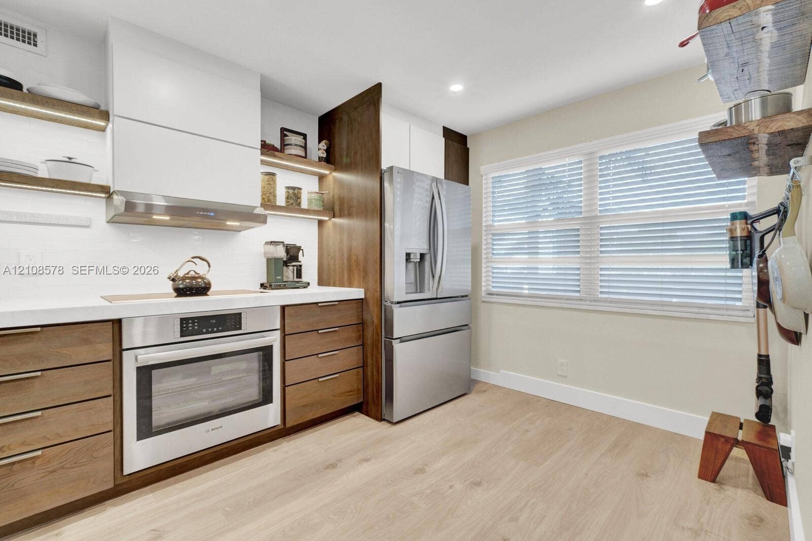 3005 Portofino Isle, #N2, Coconut Creek, Coconut Creek, FL 33066 Kitchen featuring wood-finish cabinetry, white slab countertops, stainless steel appliances, open wood shelving, and wood-finish tile flooring