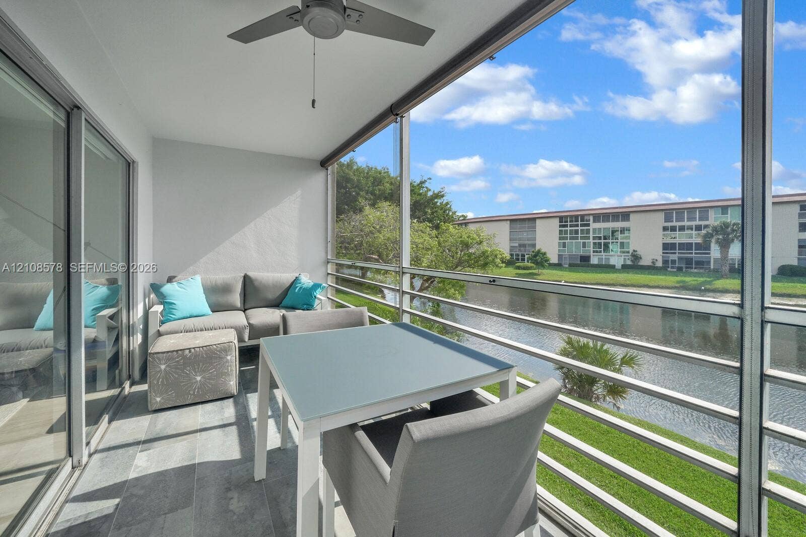 3005 Portofino Isle, #N2, Coconut Creek, Coconut Creek, FL 33066 Screened-in balcony featuring grey tile flooring, a ceiling fan, and metal railings overlooking a canal
