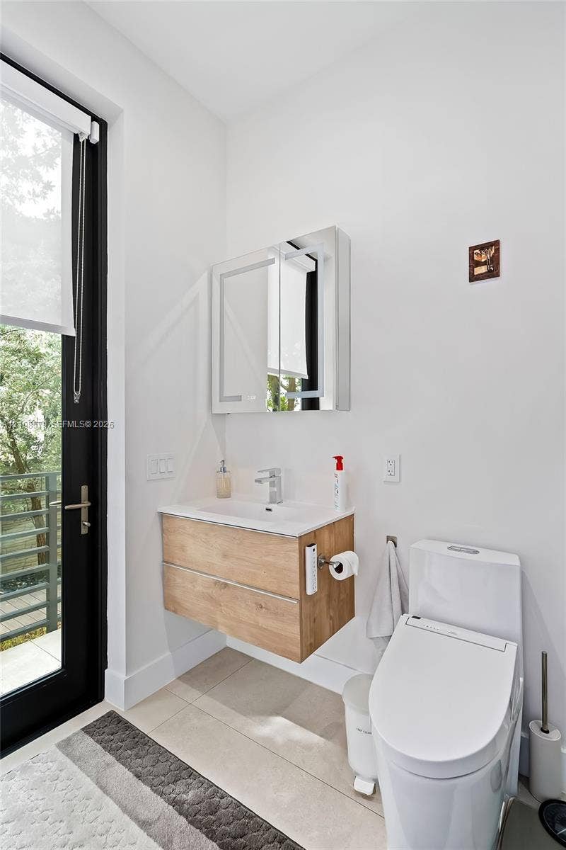 311 189th Street, #0, Sunny Isles Beach, Sunny Isles Beach, FL 33160 Wall-mounted vanity featuring wood-finish cabinetry and a white countertop, mirrored medicine cabinet, integrated sink faucet, and tile flooring