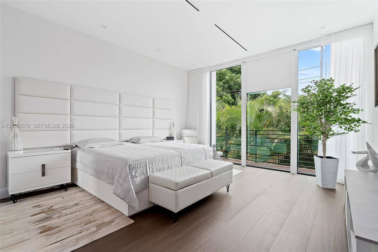 Floor-to-ceiling windows, wood-finish flooring, recessed lighting, and wall-mounted grid headboard paneling
