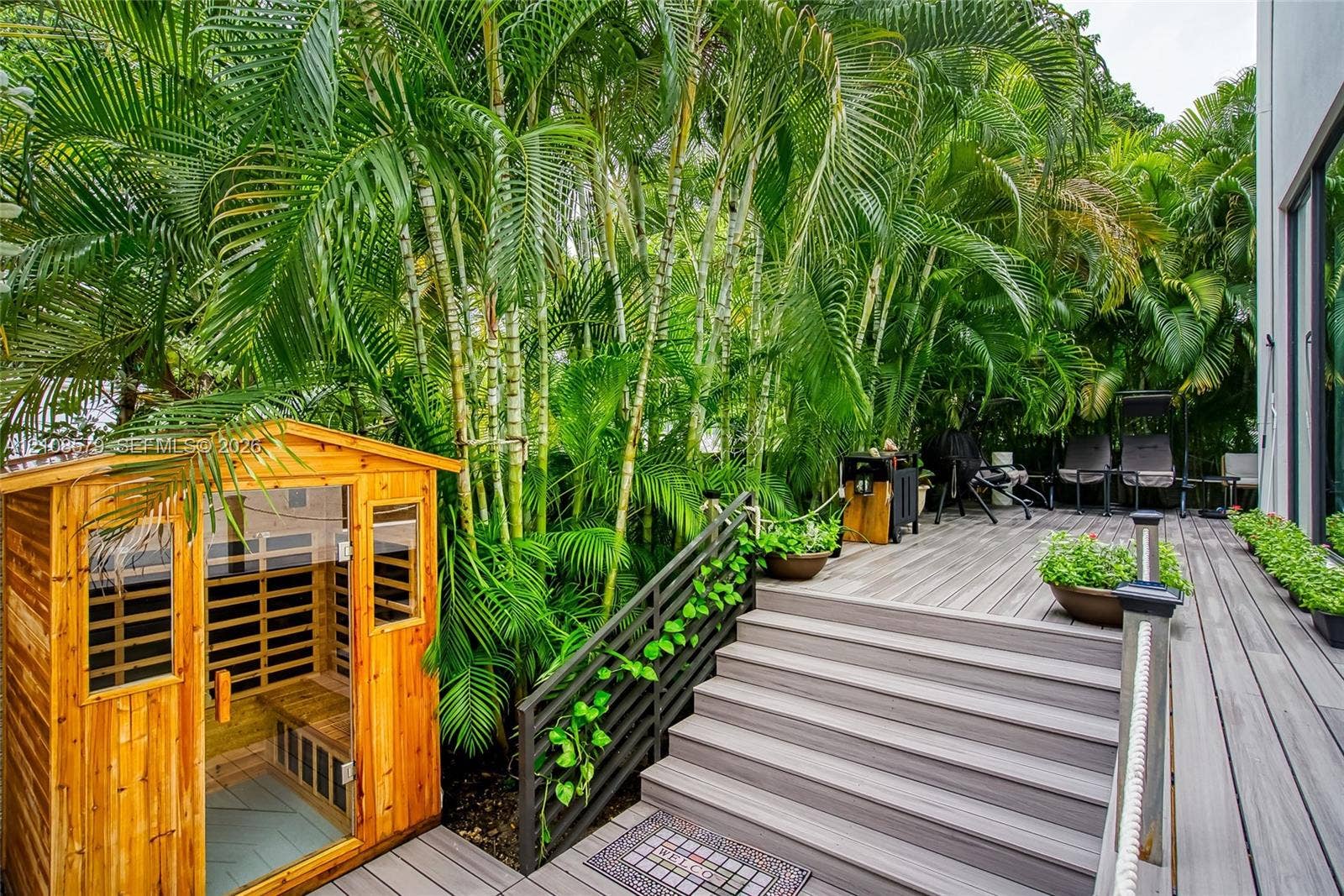 311 189th Street, #0, Sunny Isles Beach, Sunny Isles Beach, FL 33160 Multi-level composite decking, built-in wooden sauna, black metal railings, and dense mature palm landscaping