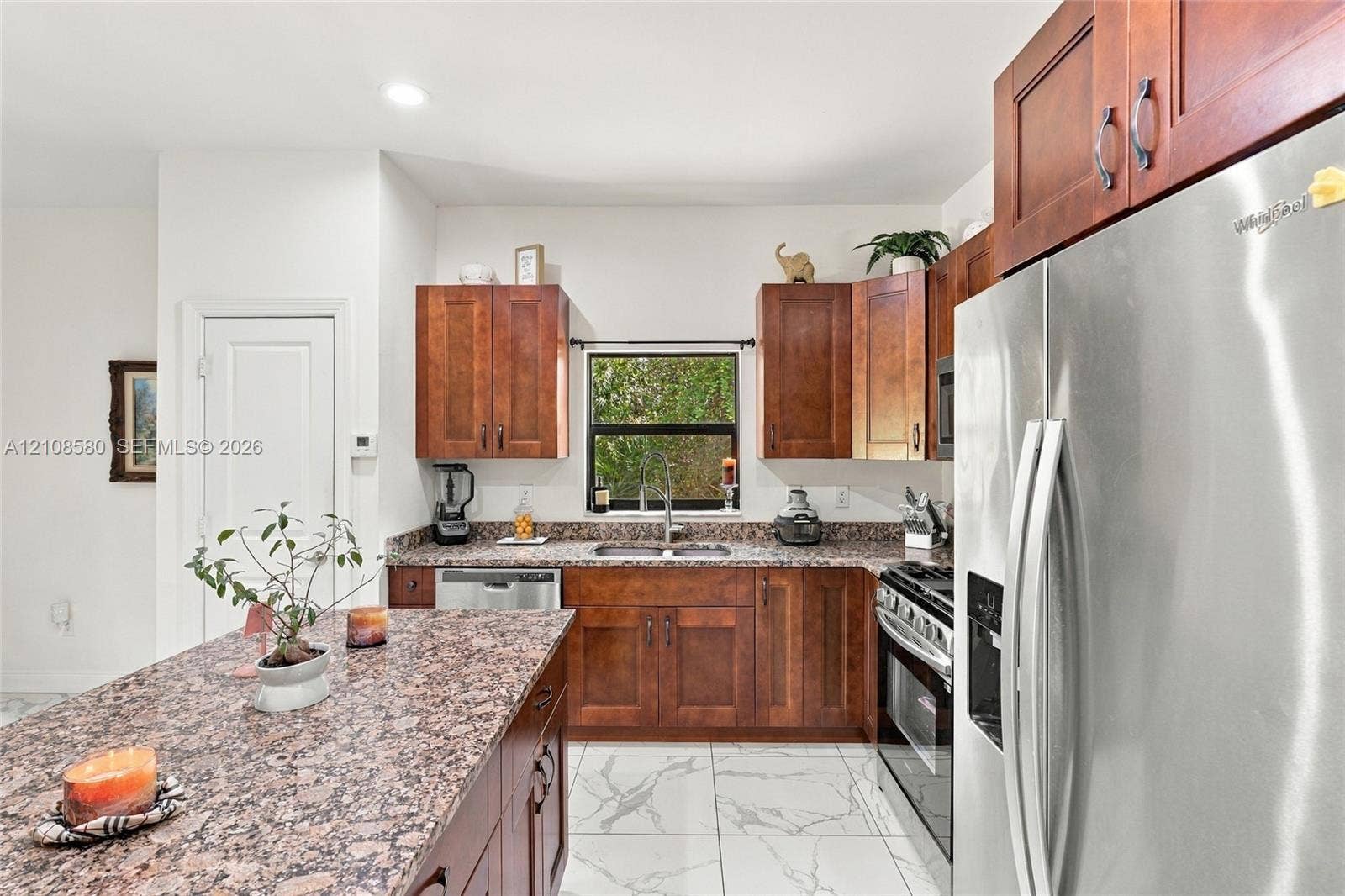 2363 NE 20 Th Avenue, Naples, FL 34120 Kitchen featuring wood cabinetry, stone countertops, a central island, stainless steel appliances, and large-format tile flooring