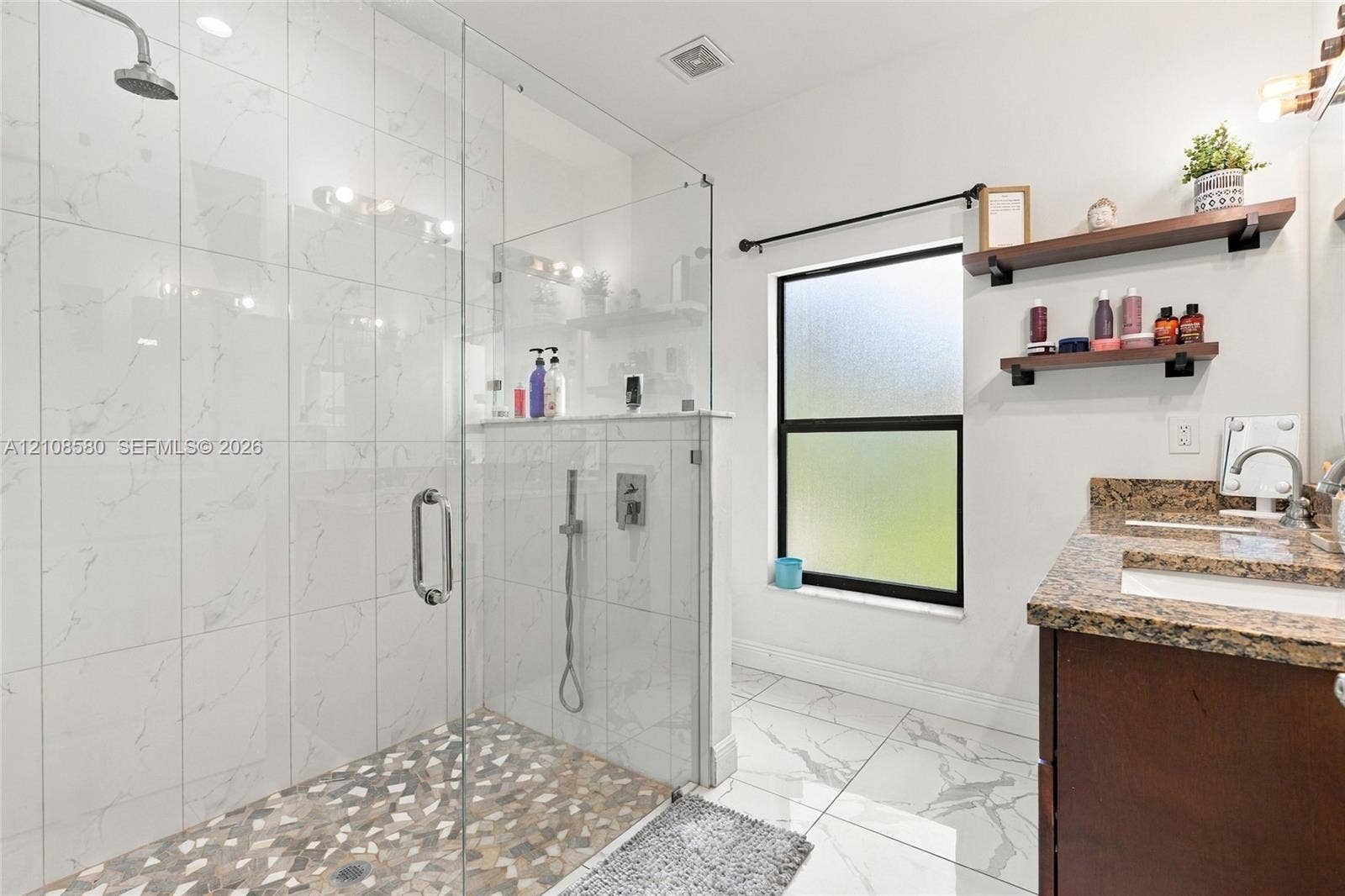 2363 NE 20 Th Avenue, Naples, FL 34120 Walk-in shower featuring glass paneling, floor-to-ceiling tile surround, and a pebble-stone floor finish