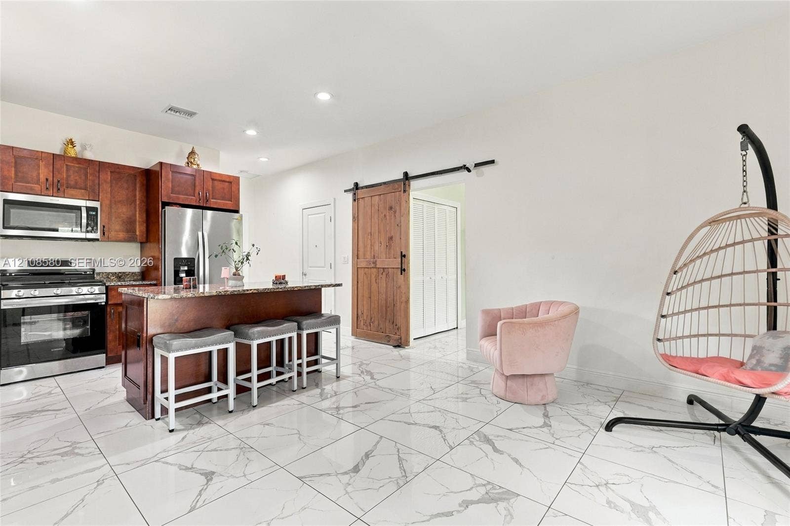 2363 NE 20 Th Avenue, Naples, FL 34120 Kitchen featuring wood cabinetry, stone-finish countertops, stainless steel appliances, polished stone-finish flooring, and a sliding barn door