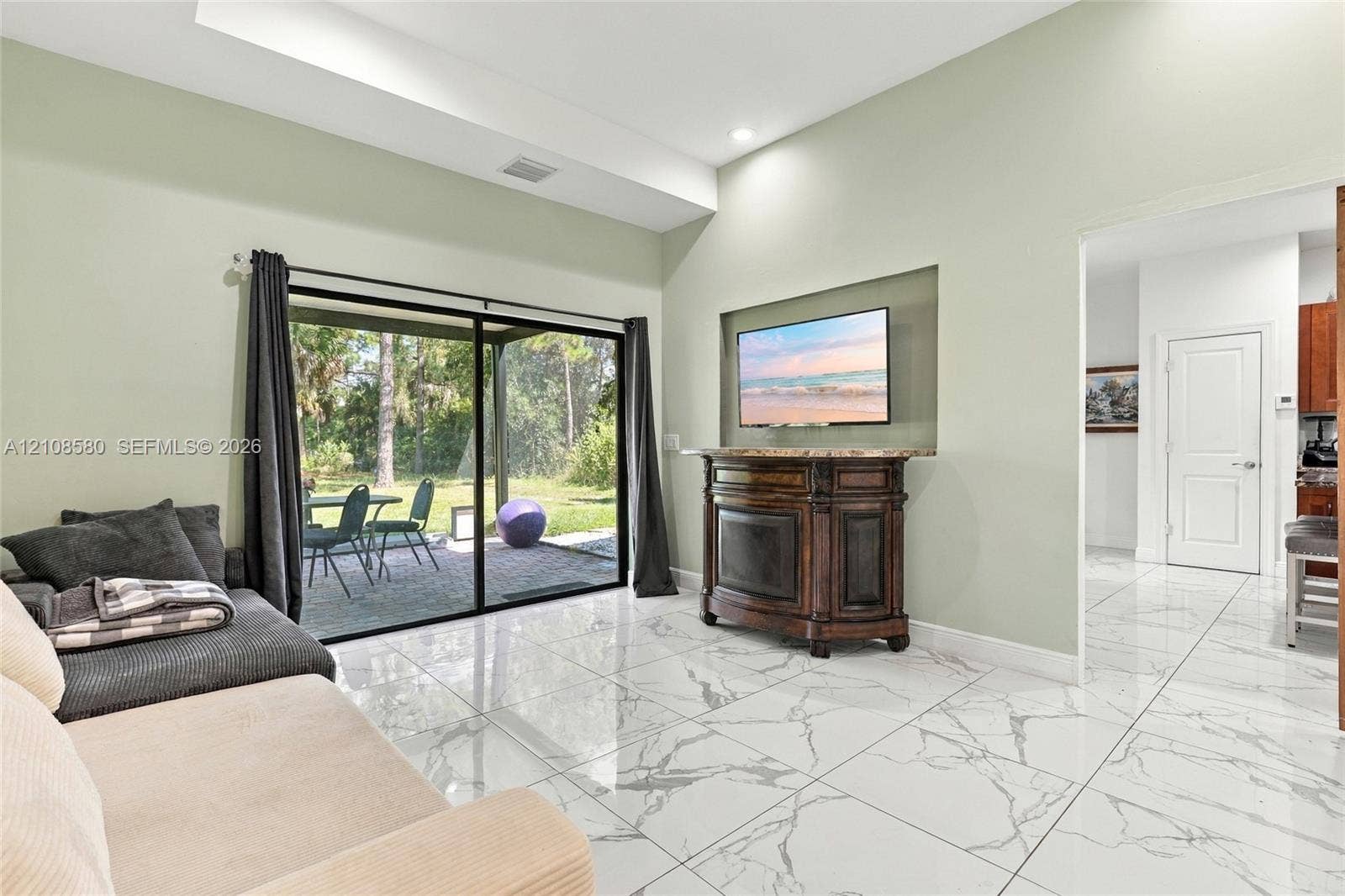 2363 NE 20 Th Avenue, Naples, FL 34120 Vaulted ceilings, large-format tile flooring with a marble-style finish, recessed wall niche, and sliding glass doors with access to a paved patio