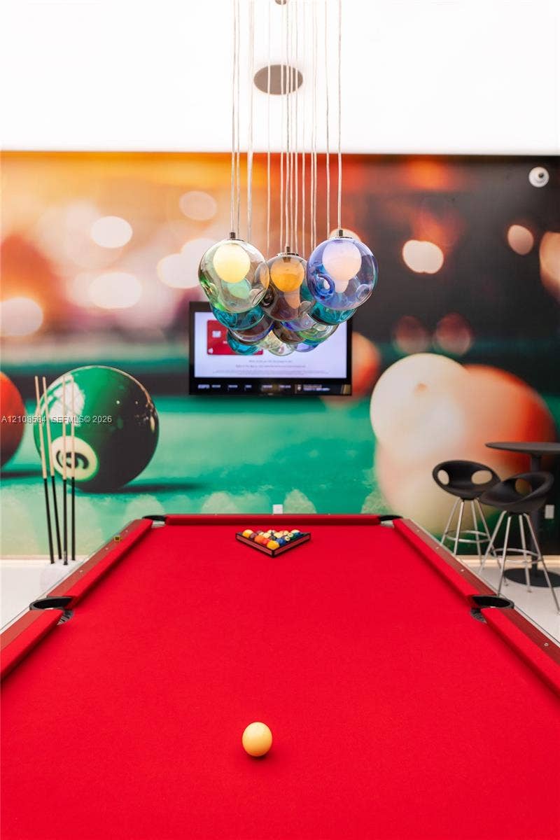 Custom multi-colored glass pendant lighting fixture featuring cascading globes and wall-mounted television screen