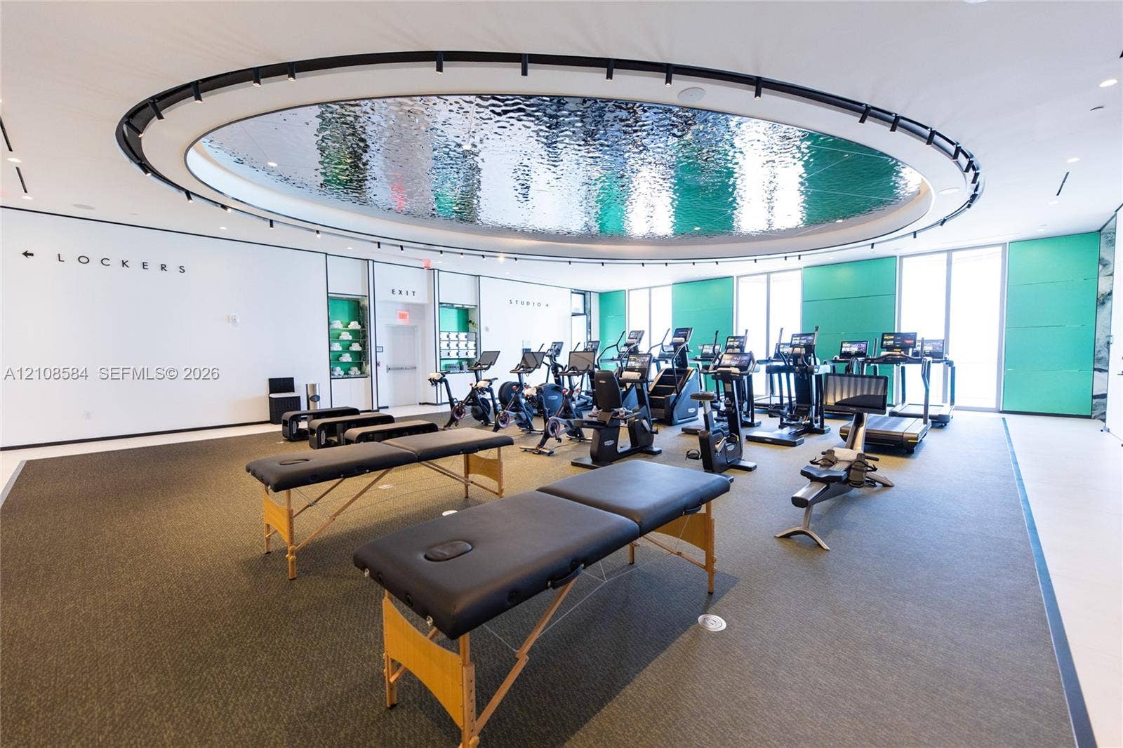 Fitness center featuring a circular recessed ceiling with a reflective metallic finish, floor-to-ceiling windows, and recessed track lighting