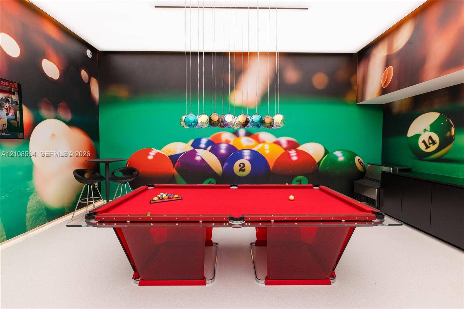 Custom game room featuring a multi-pendant light fixture, built-in matte black cabinetry, and smooth flooring