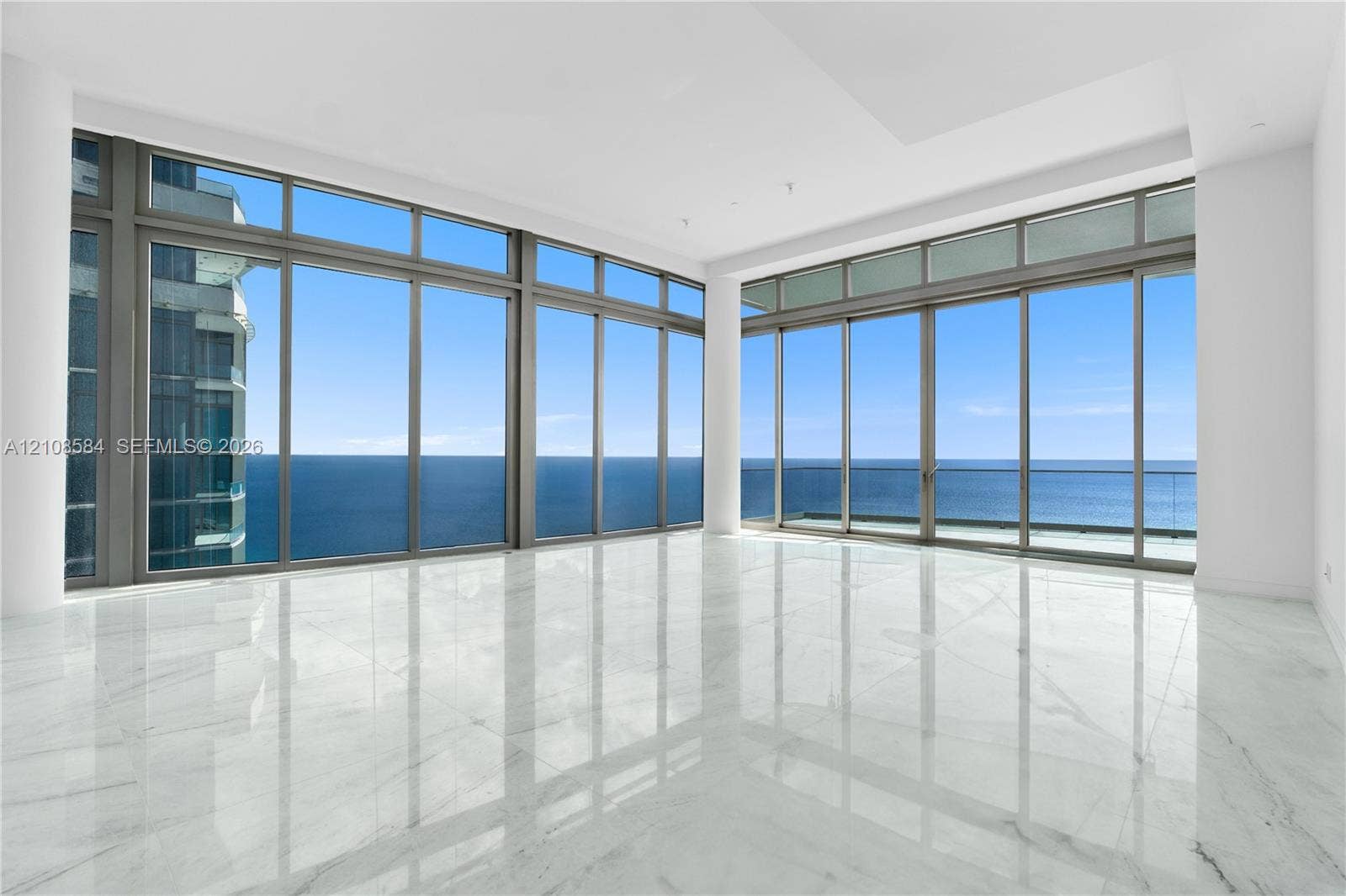 Floor-to-ceiling windows, polished stone flooring, recessed ceiling lighting, and a glass-paneled balcony