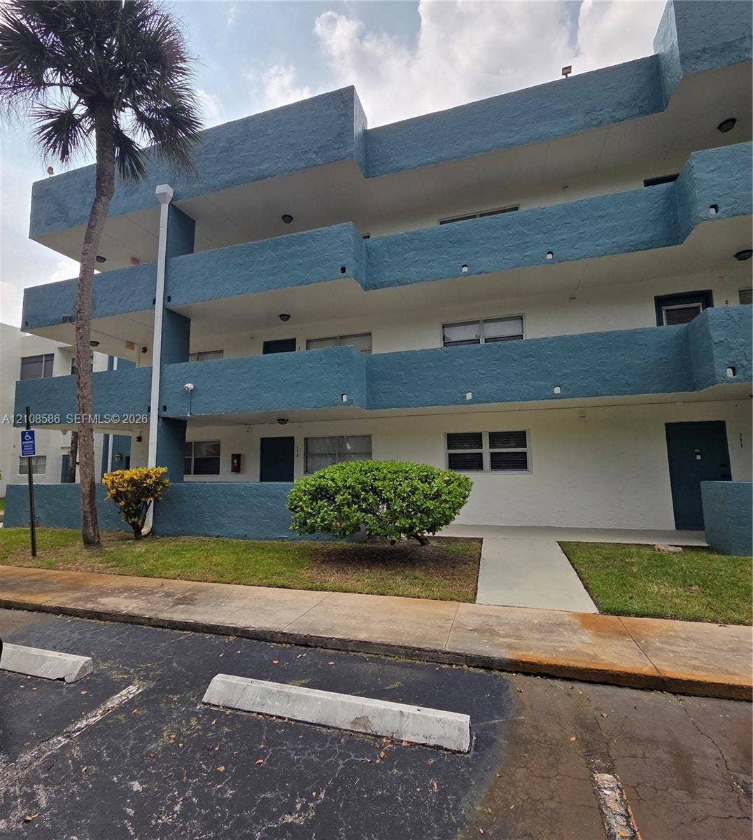 6075 N Sabal Palm Boulevard, #110, Tamarac, FL 33319 Multi-story building exterior featuring a textured stucco facade with recessed balconies and integrated surface lighting