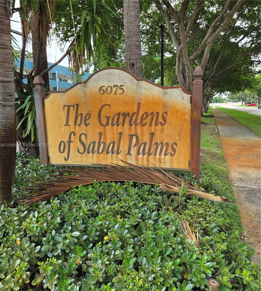 6075 N Sabal Palm Boulevard, #110, Tamarac, FL 33319 Custom monument sign featuring decorative wooden posts and mature landscape hedging