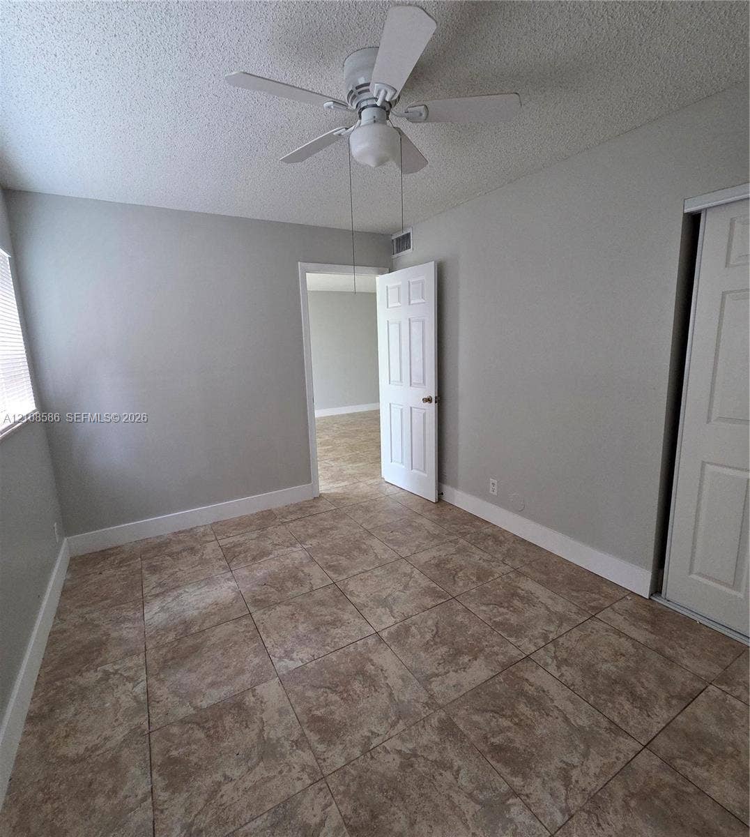 6075 N Sabal Palm Boulevard, #110, Tamarac, FL 33319 Neutral-toned interior featuring ceramic tile flooring, a central ceiling fan with integrated light fixture, and six-panel interior doors