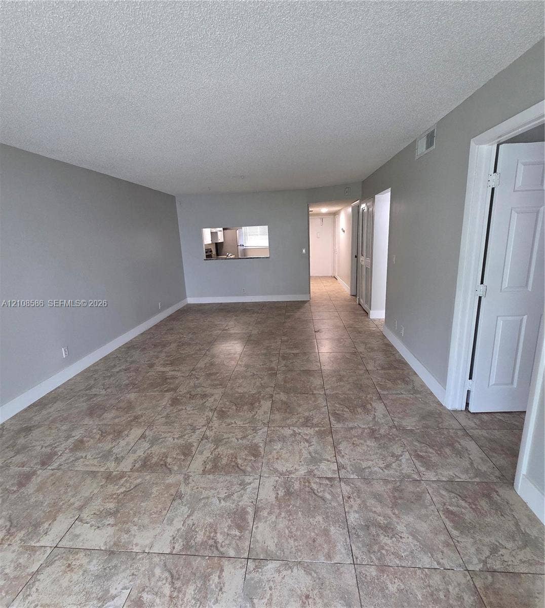 6075 N Sabal Palm Boulevard, #110, Tamarac, FL 33319 Neutral-toned interior featuring large-format ceramic floor tile, pass-through opening, and six-panel interior doors