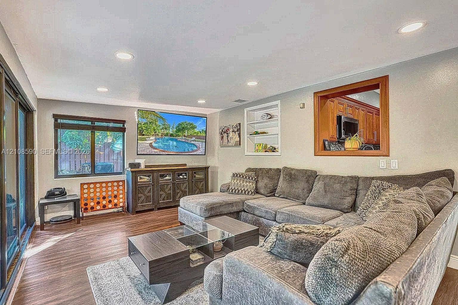 1728 NE 17th Terrace, Fort Lauderdale, Fort Lauderdale, FL 33305 Living area featuring wood-finish flooring, recessed lighting, built-in wall shelving, and a wood-framed interior window
