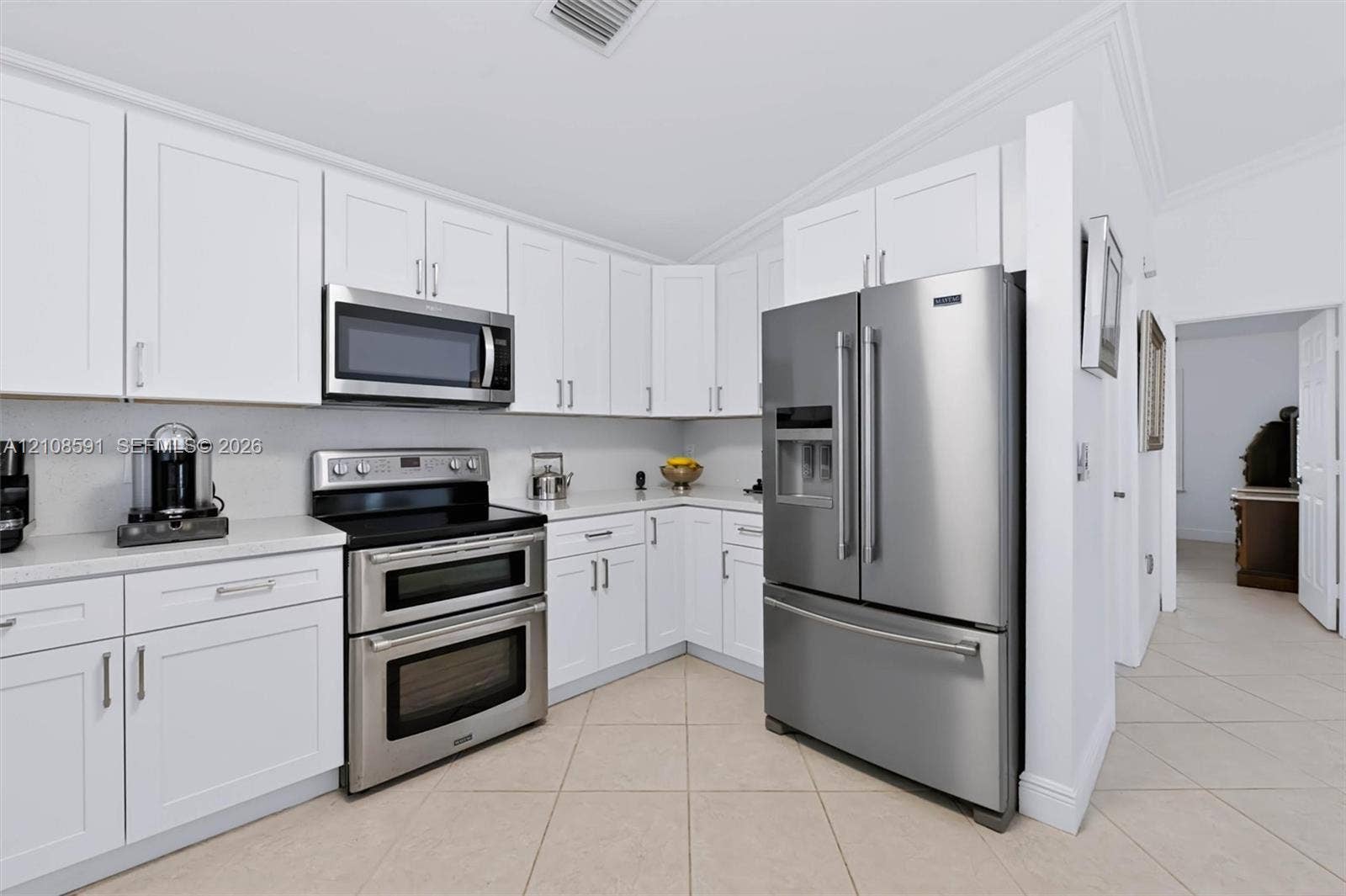 415 SW 200th Terrace, Pembroke Pines, FL 33029 Kitchen featuring white shaker-style cabinetry, solid-surface countertops, and stainless steel appliances including a dual-oven range, built-in microwave, and French-door refrigerator
