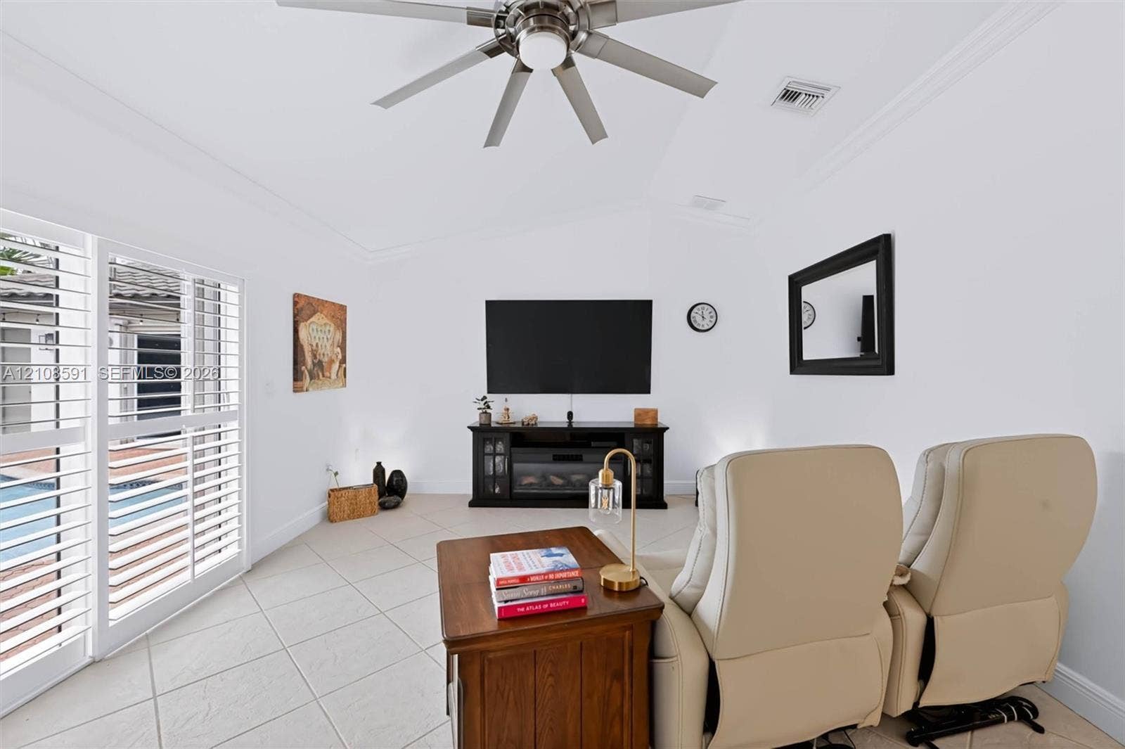 415 SW 200th Terrace, Pembroke Pines, FL 33029 Vaulted ceiling with a central brushed-nickel ceiling fan, large-format tile flooring, and sliding glass doors featuring white plantation shutters