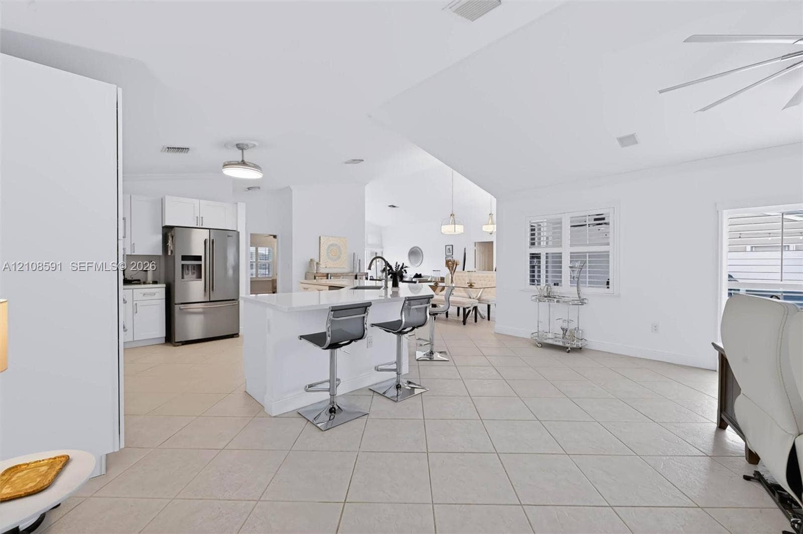 415 SW 200th Terrace, Pembroke Pines, FL 33029 Open-concept kitchen featuring white shaker-style cabinetry, quartz countertops, a central island, tile flooring, and vaulted ceilings