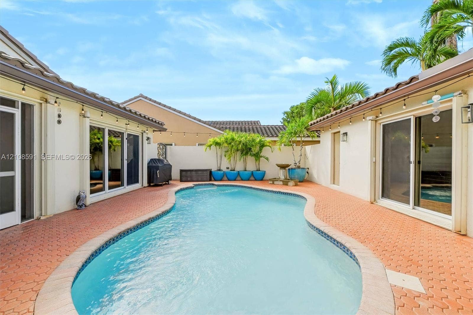 415 SW 200th Terrace, Pembroke Pines, FL 33029 Enclosed courtyard featuring a swimming pool, terracotta-style paved patio, white perimeter wall, and sliding glass door access