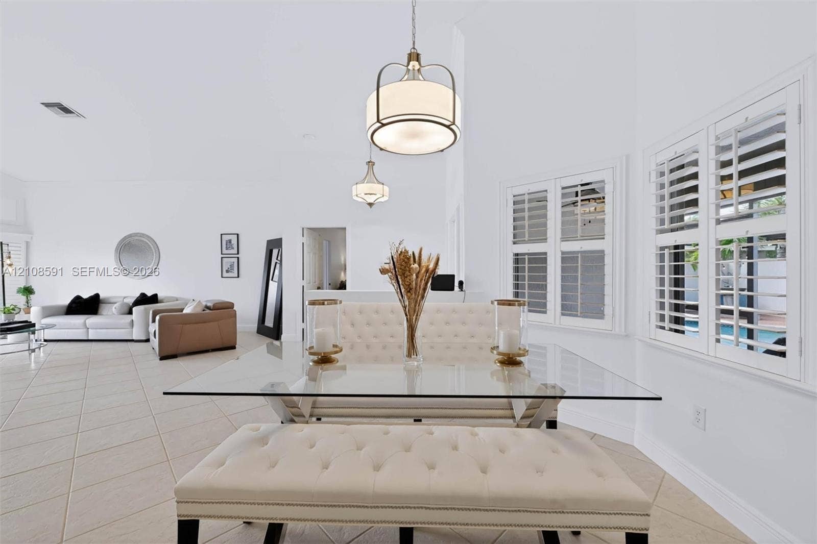 415 SW 200th Terrace, Pembroke Pines, FL 33029 High-ceilinged room featuring large-format ceramic tile flooring, dual drum-style pendant light fixtures, and white plantation shutters