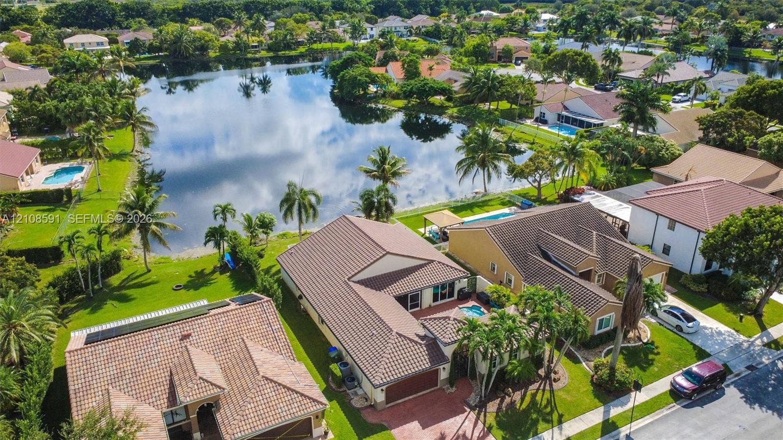 415 SW 200th Terrace, Pembroke Pines, FL 33029 Aerial perspective featuring a tile roof, paved driveway, swimming pool, and direct lake frontage