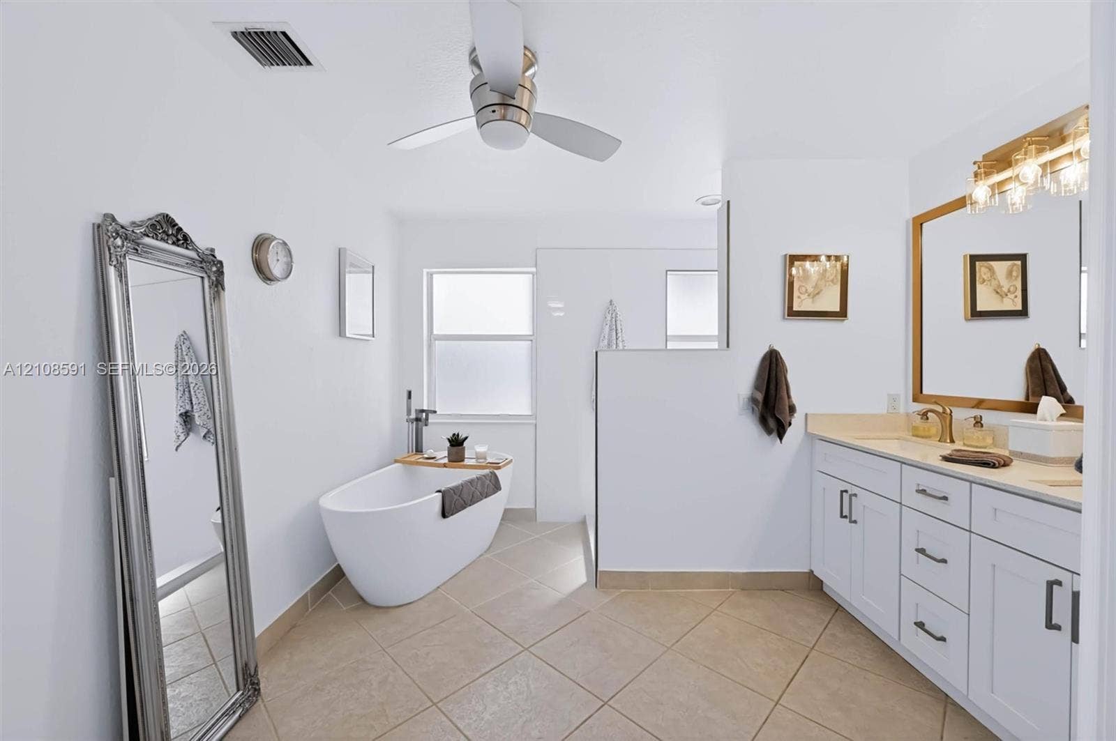 415 SW 200th Terrace, Pembroke Pines, FL 33029 Bathroom featuring a freestanding soaking tub, white shaker-style cabinetry with neutral solid-surface countertops, tile flooring, and a multi-light vanity fixture