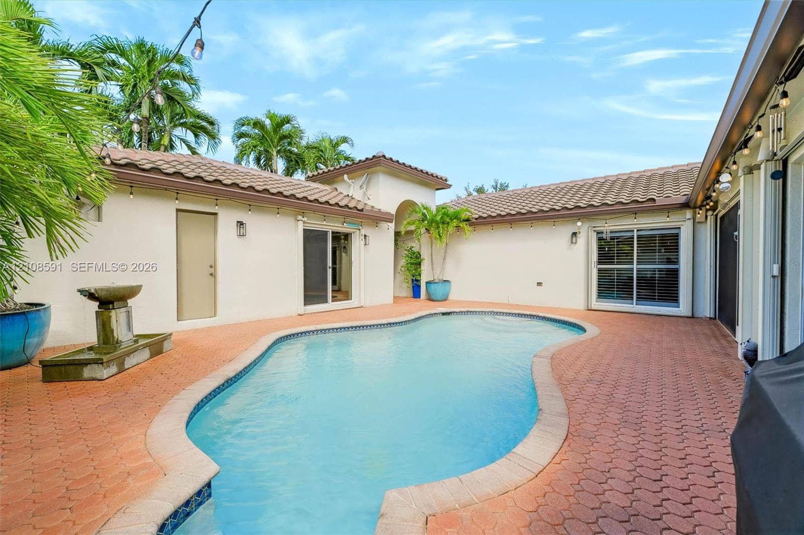 415 SW 200th Terrace, Pembroke Pines, FL 33029 Courtyard pool featuring paved hardscaping, stucco exterior, clay-tile roofing, and a built-in stone water feature