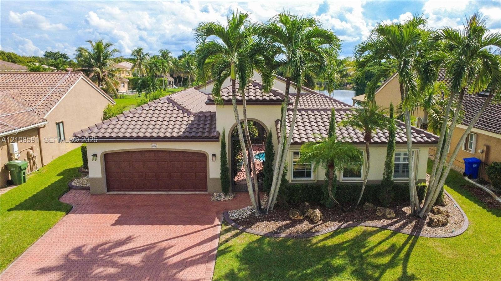 415 SW 200th Terrace, Pembroke Pines, FL 33029 Single-story residence featuring a tile roof, arched entryway, two-car garage, brick-paver driveway, and mature landscaping