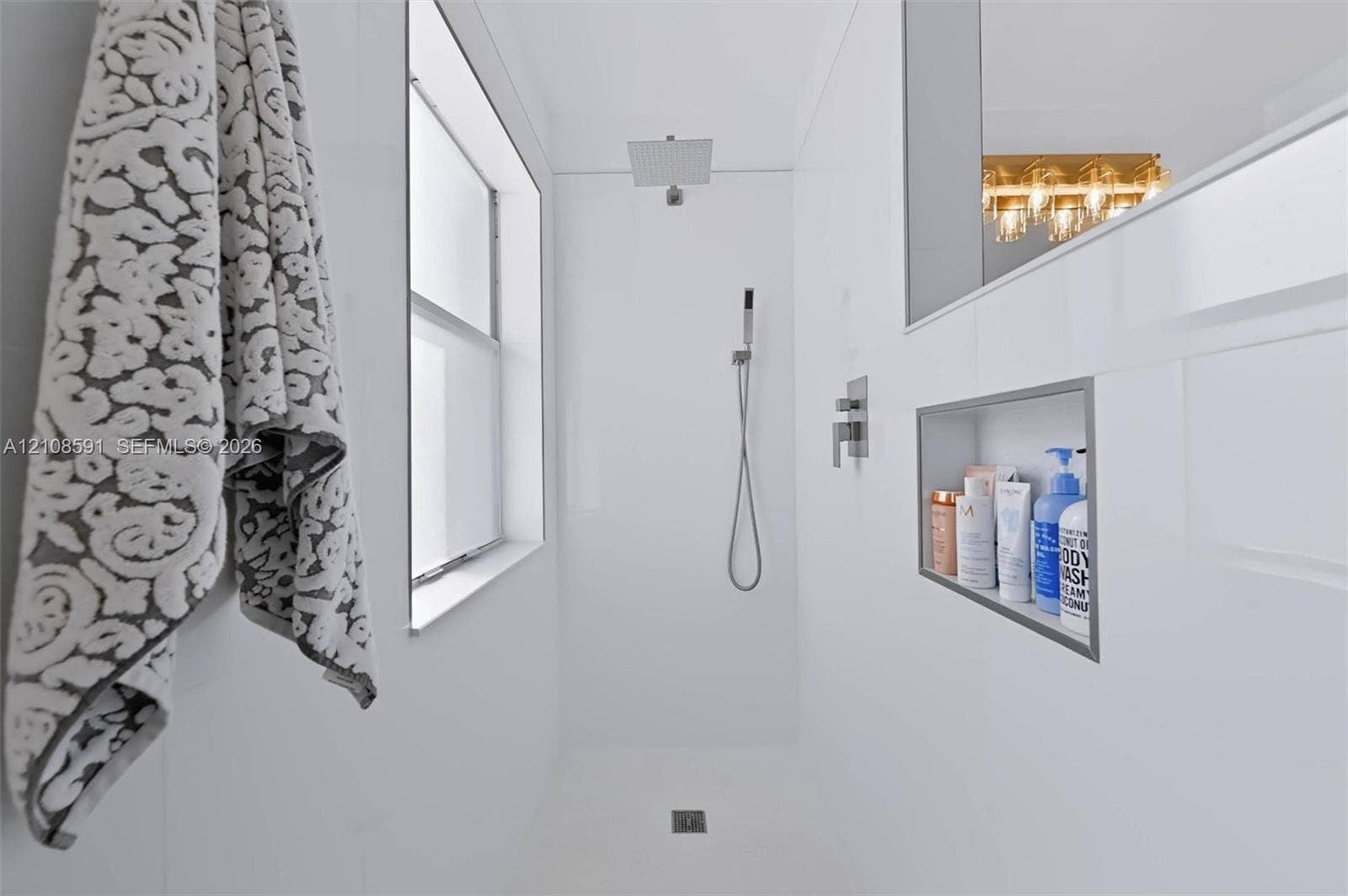 415 SW 200th Terrace, Pembroke Pines, FL 33029 Walk-in shower featuring white wall panels, a square rainfall showerhead, a separate handheld sprayer, and a built-in recessed storage niche
