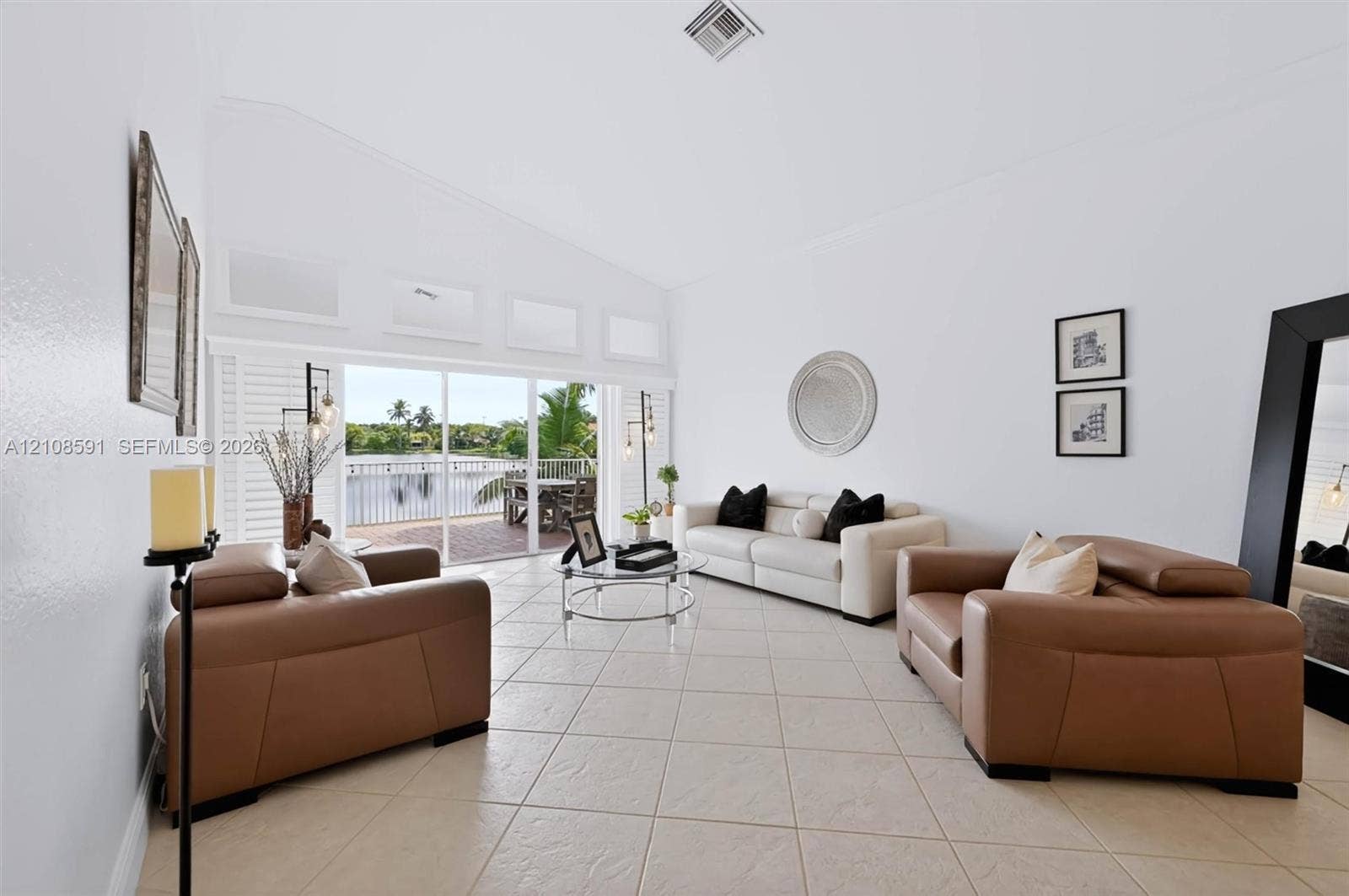 415 SW 200th Terrace, Pembroke Pines, FL 33029 Living area featuring vaulted ceilings, oversized tile flooring, clerestory windows, and sliding glass doors opening to a waterfront balcony